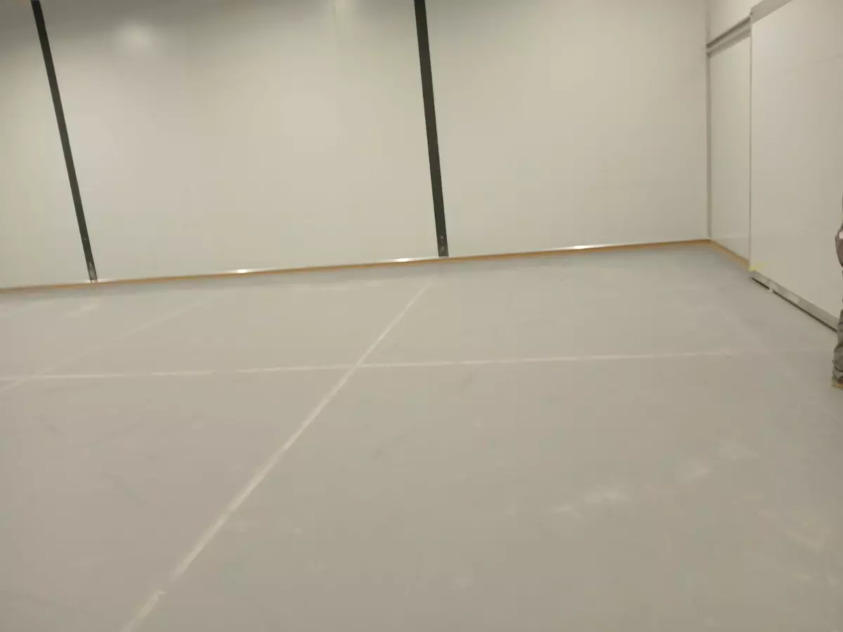 Empty room with white panel walls and grey floor